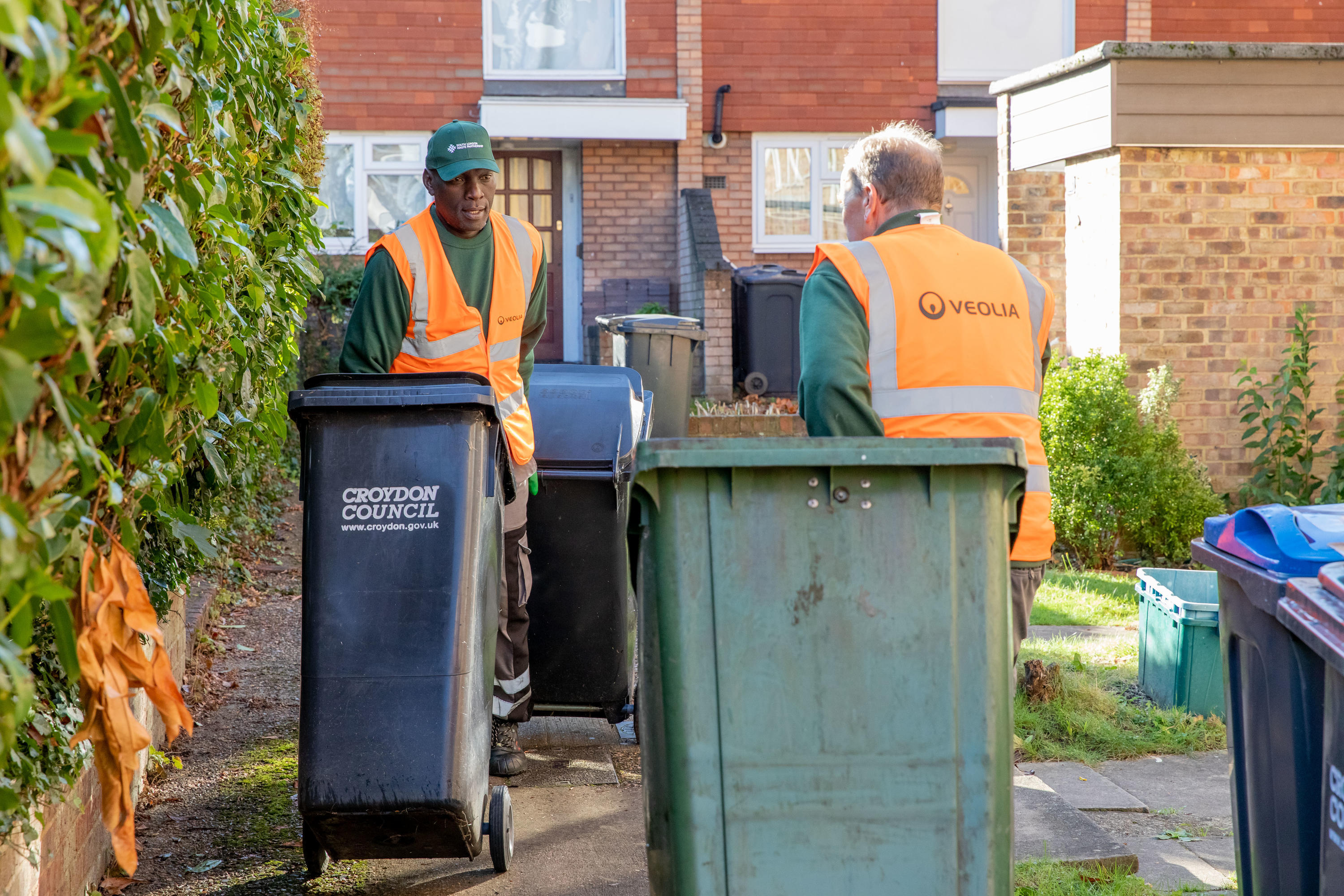 Two waste collection operatives collecting wheelie bins in Croydon